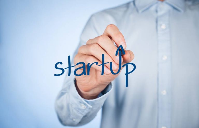 Homem engravatado escreve o nome "startup", representando essa nova forma de fazer negócios