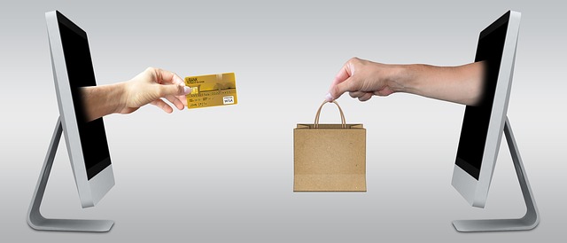 Dois computadores, um de frente para o outro, trocando uma sacola de compras por um cartão de crédito, representando o ecommerce