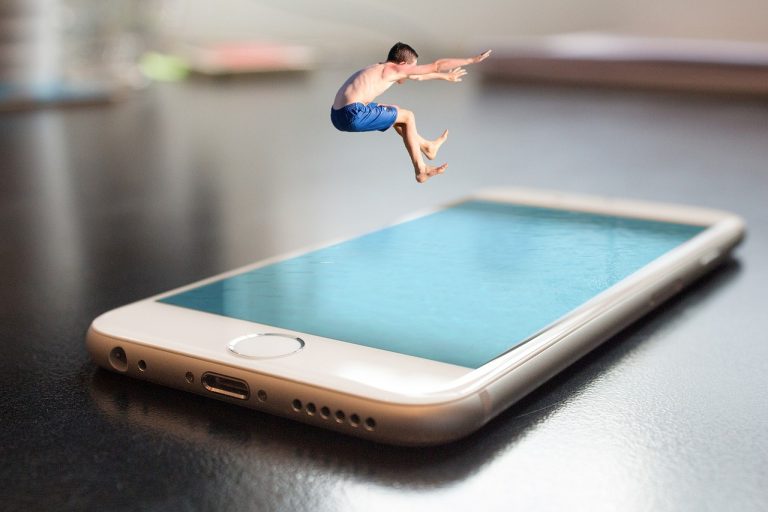 Menino pulando em uma piscina, só que a piscina é representada por um smart phone, representando o comércio eletrônico no verão