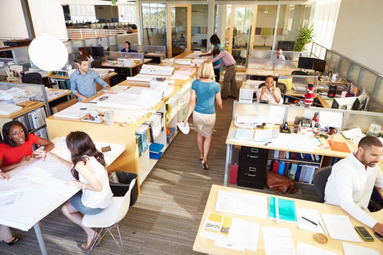 Espaço de coworking com pessoas trabalhando em suas mesas e computadores